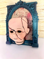 Broken doll art with decorative frame